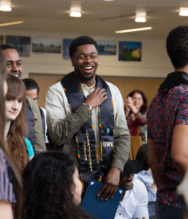 A student smiles during commencement, proudly representing the Intercultural Center